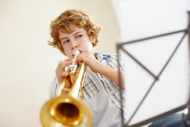 Photo playing music and child with notes and trumpet for practice jazz lesson and learning for talent show musician creative hobby and young boy with instrument sheet and paper on song melody at home