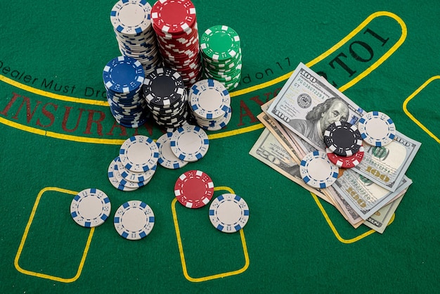 On the playing poker table are colored chips on top of each other and dollars next to them