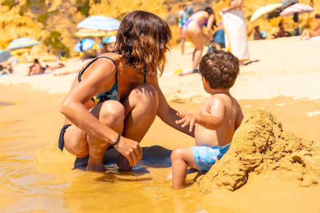 Playing in the sand on the beach at Praia do Barranco das Belharucas Albufeira Algarve Portugal