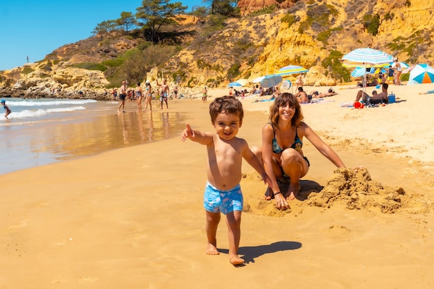 Playing in the sand on the beach at Praia do Barranco das Belharucas Albufeira Algarve Portugal