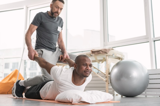 Pleasant activity. Nice happy man smiling while enjoying the rehabilitation workout