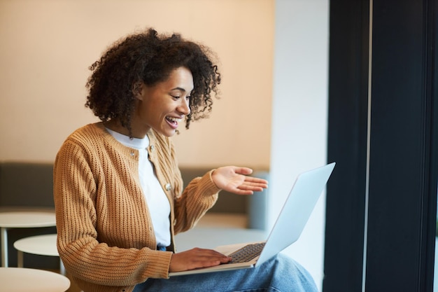 Pleasant African American young woman using laptop having an online conference by video link