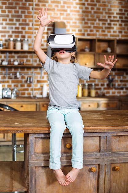 Photo pleasant little girl wearing vr device while sitting on the table