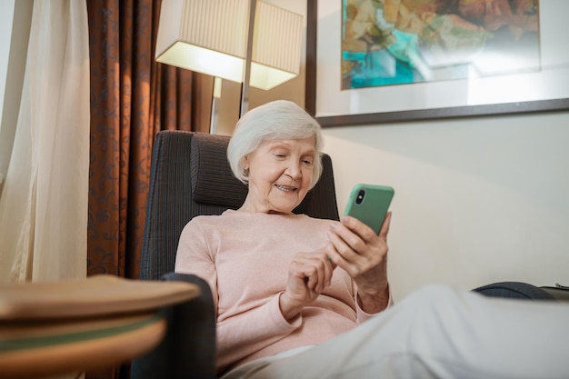 Pleasant-looking senior lady texting and looking involved