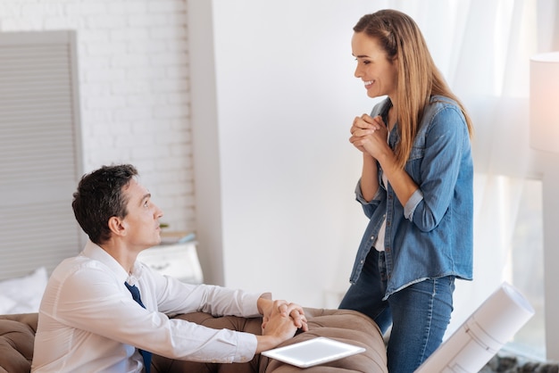 Pleasant news. Cheerful smiling young woman looking happy and excited while looking at her husband and telling him about her new interesting job