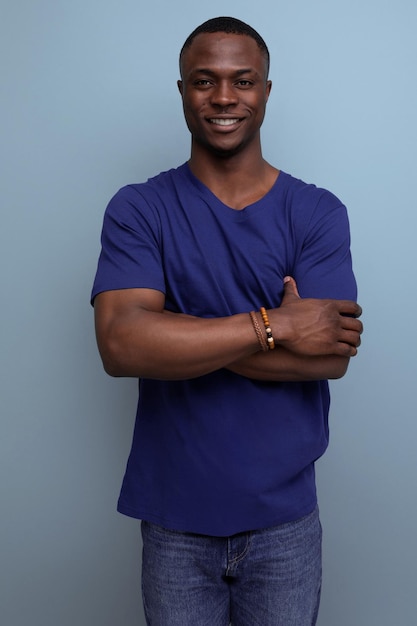 Pleasant wellgroomed cute young african man in a blue tshirt on a blue background