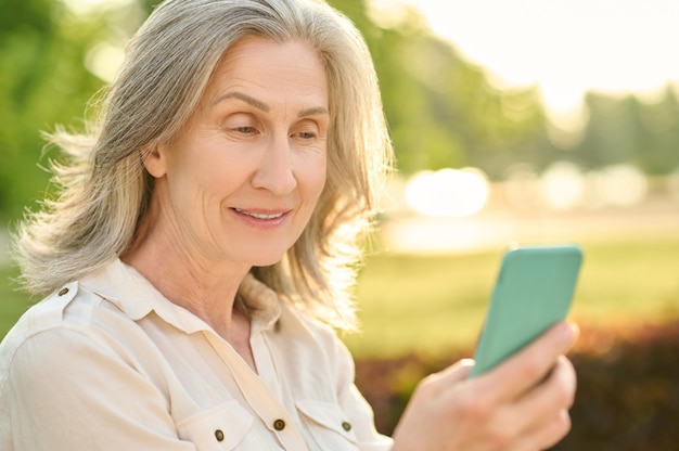 Pleasantly surprised woman looking at smartphone screen