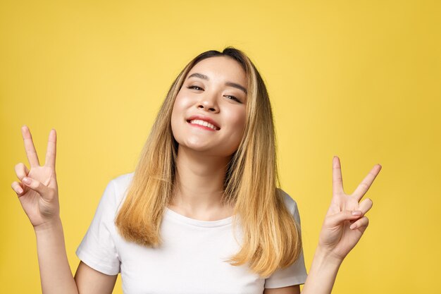 Pleased asian woman in t-shirt showing peace gestures