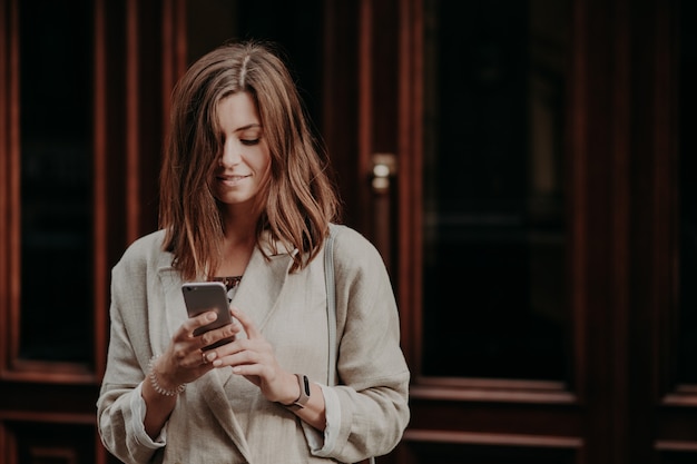 Pleased delighted female youngster watches video on smart phone