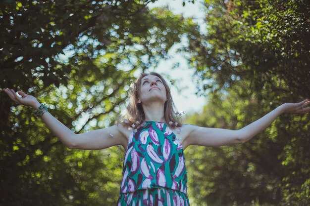 Photo pleased girl in summer dress spreading arms scenic photography