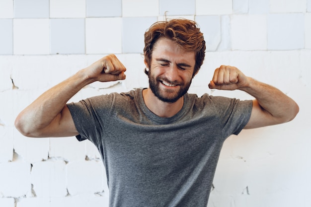 Pleased joyful bearded man against rough wall, portrait