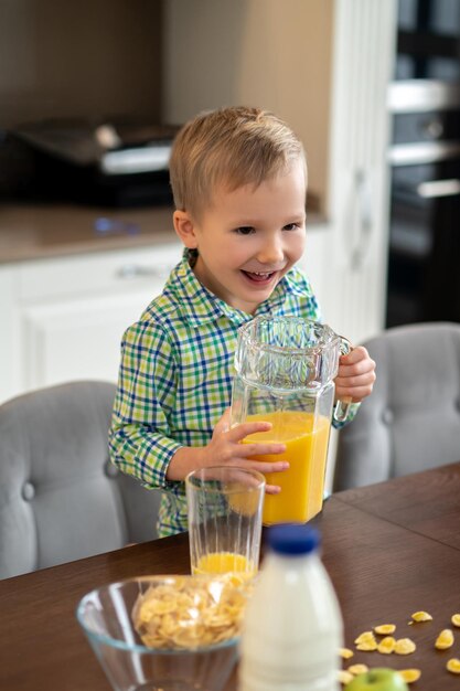 Pleased kid with a glass pitcher in the kitchen