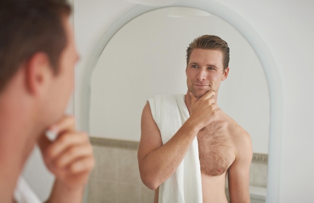 Pleased with his reflection A young man looking at his reflection in the mirror after a shave