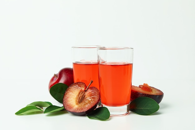 Plum brandy shots and ingredients on white background