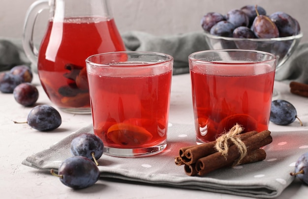 Plum Compote in jug and two glasses on light gray background