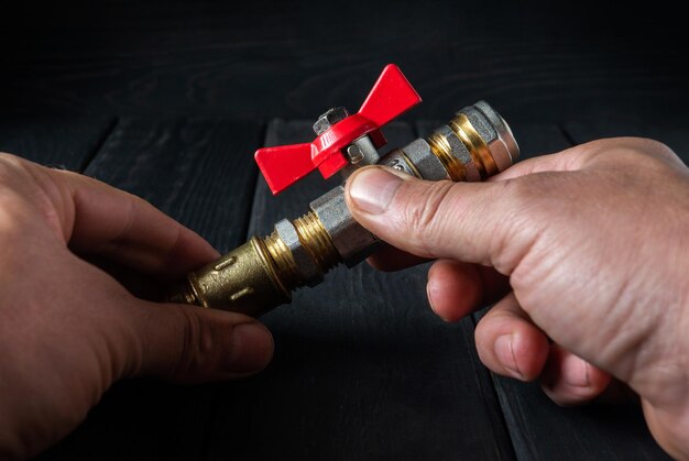 The plumber connects brass fittings to ball valve Closeup of the hand of the master while working