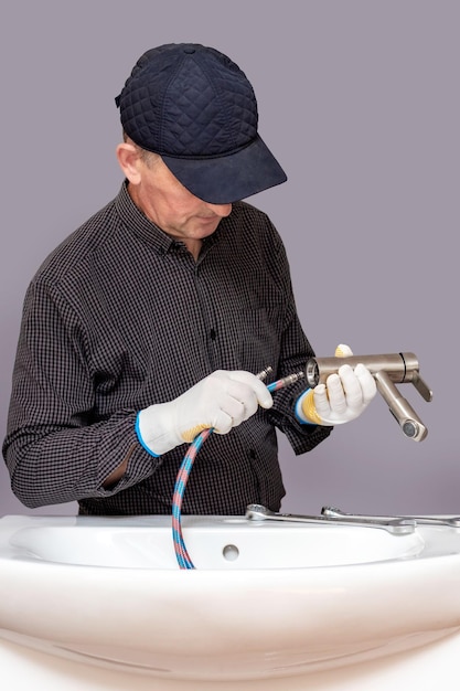 A plumber installs a faucet in a bathroom connects a hose to the faucet