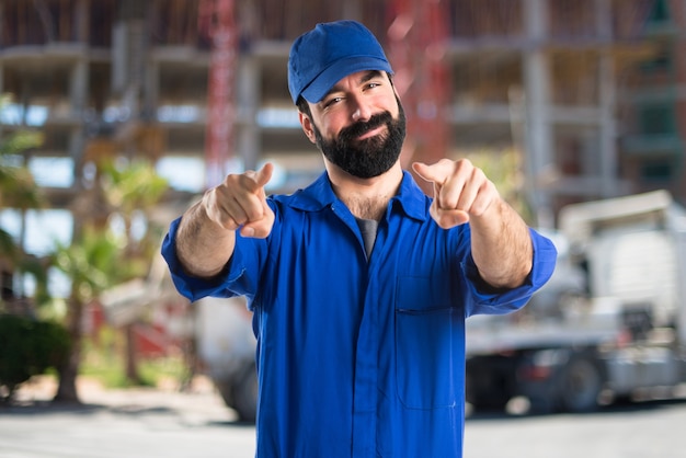 Plumber pointing to the front on unfocused background