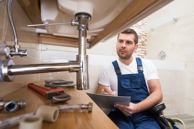 Plumber with tablet repairing sink