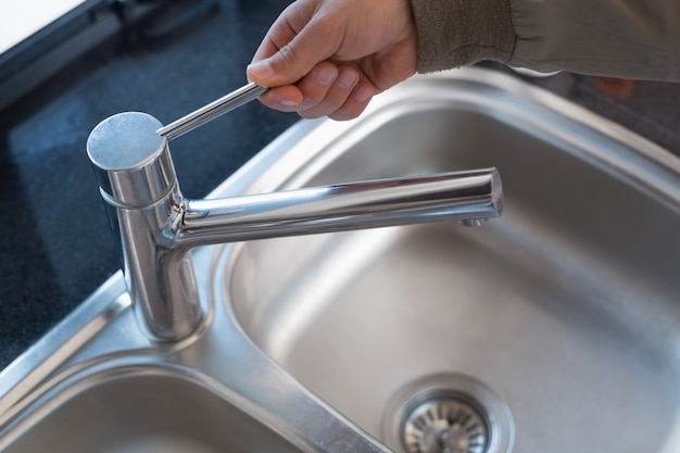 Plumbers hand opening a water tap at bathroom