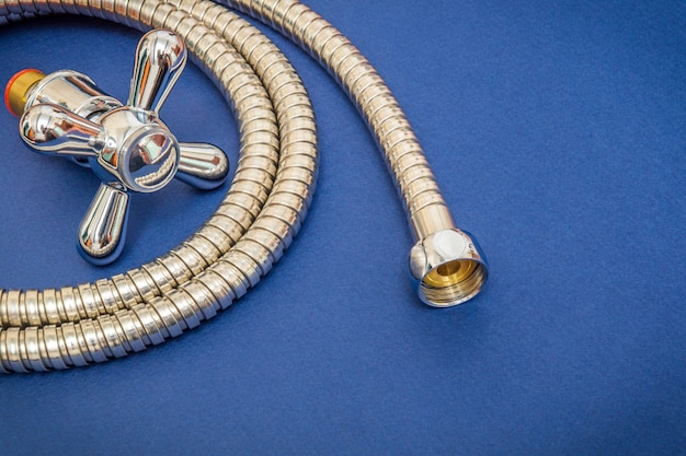 Plumbing materials faucet and hose on a blue space are used for replacement in the shower