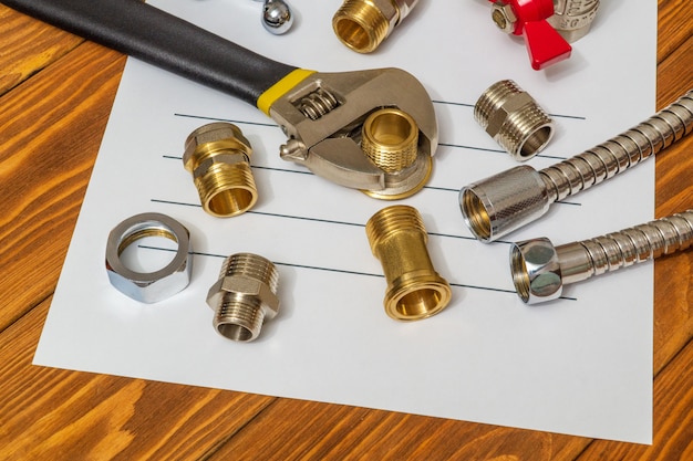 Plumbing spare parts and adjustable spanner closeup on the sheet for notes and preparation of a repair plan