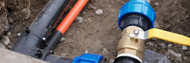 Plumbing with faucet in recess in ground close up plastic water pipeline and metal tap outdoors