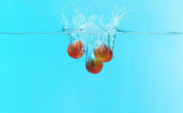 Plums falling into water on color background