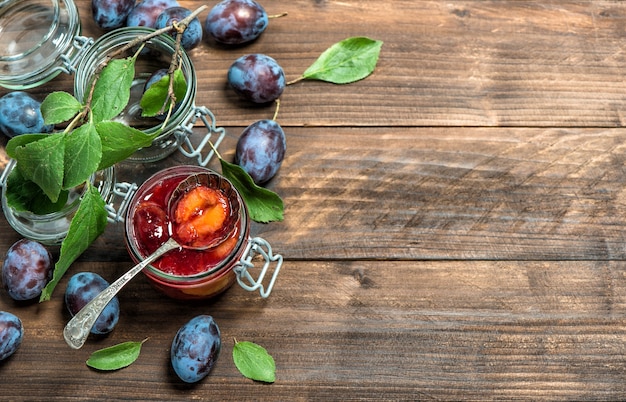 Plums jam on rustic wooden background. Fruit marmalade