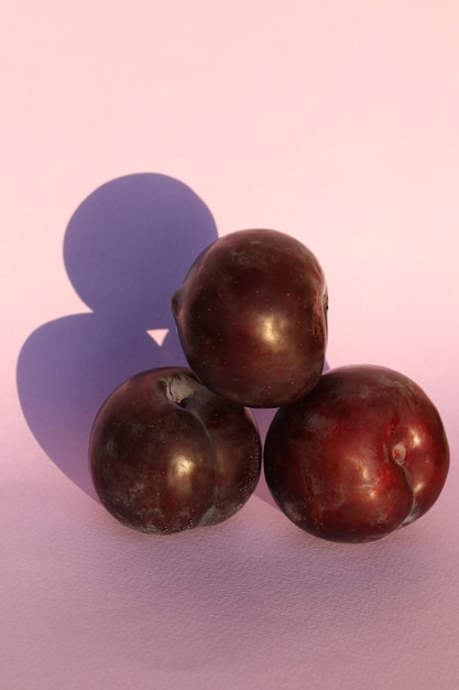 plums on the pink background with copy space