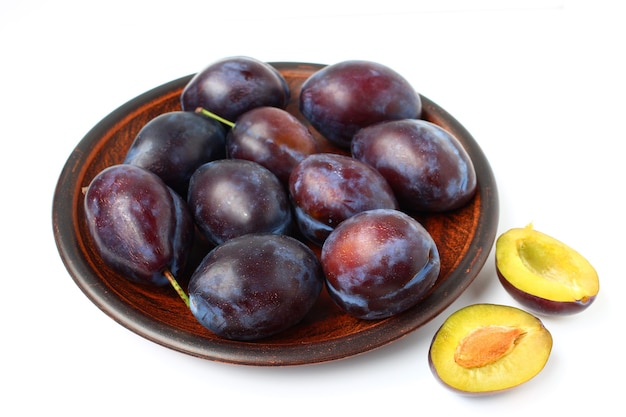 Plums in a plate on a white surface