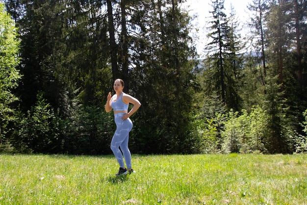 Plus size girl doing physical exercise sports and running in a blue tight suit outdoors