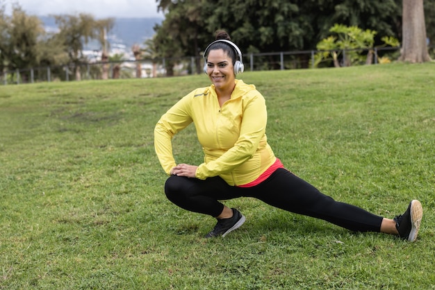 Photo plus size girl doing stretching day routine outdoor at city park - focus on face