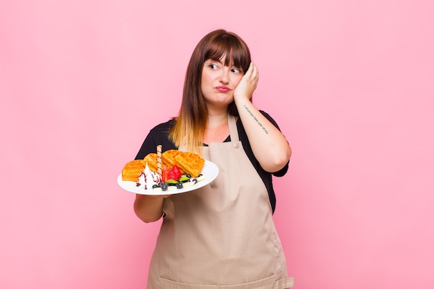 Plus size woman feeling bored, frustrated and sleepy after a tiresome, dull and tedious task, holding face with hand