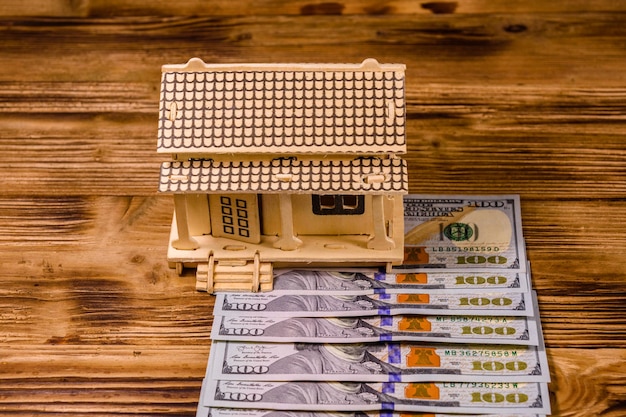 Plywood model of the house and one hundred dollar banknotes Loan real estate concept