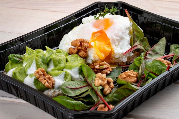 Poached egg with salad and nuts in containers on a white wooden background Takeaway Diet and healthy food