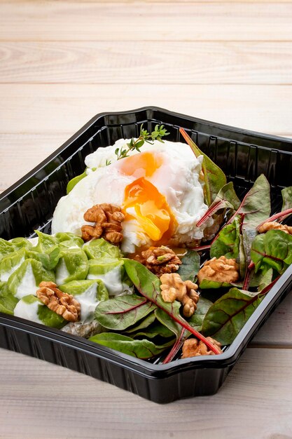 Poached egg with salad and nuts in containers on a white wooden background Takeaway Diet and healthy food