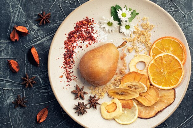 Poached pears with spices in syrup on the white plate decorated by fruits.
Delicious dessert for holiday.