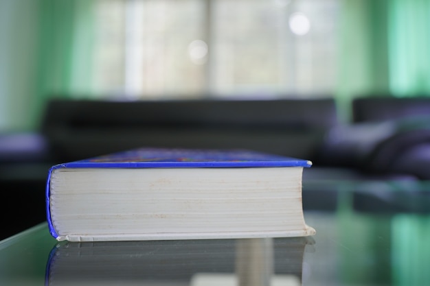 pocket book on topglass table with blur sofa set in the room