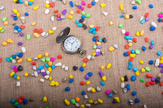 Pocket watch amid Colorful pebbles