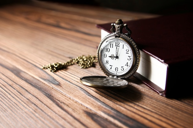 A pocket watch with book on wooden table