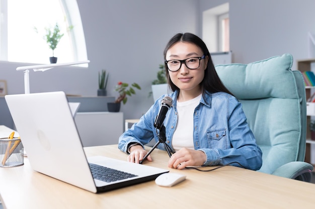 Podcast recording interview young beautiful asian woman sitting at a table with a microphone and a