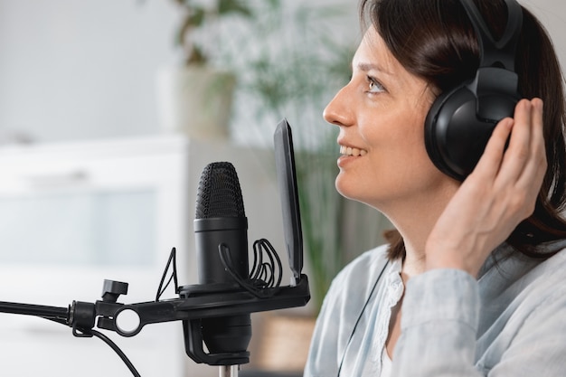 Podcaster creates content european woman records podcast with microphone and headphones caucasian