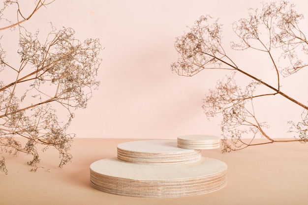 Podium of three wooden cylinders made of natural wood with dried flowers Minimalistic branding scene