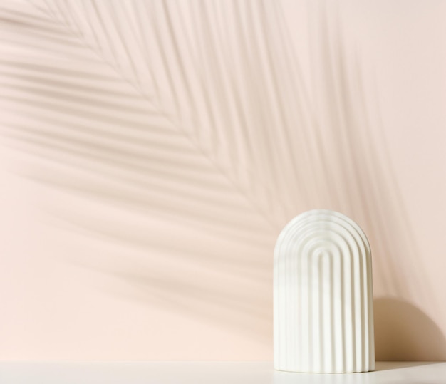 Podium with white arche to showcase cosmetics, products and other merchandise. Shadow palm leaf