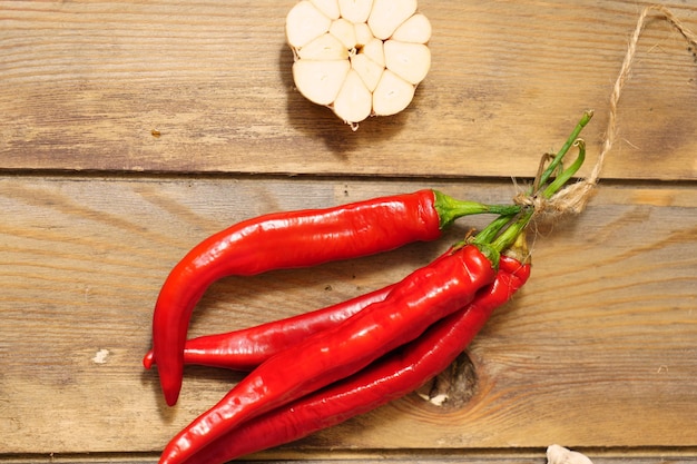 Pods of red chili pepper and garlic cut in half on a wooden background