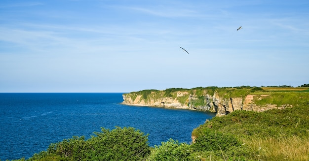 Pointe du Hoc cliffs in clear sky and calm sea.