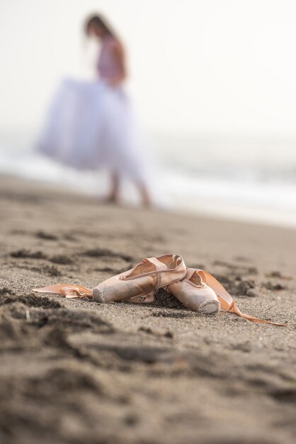 Photo pointe shoes on the sand a ballerina in the background