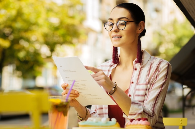 Pointing. Calm confident woman smiling and choosing meals from the menu