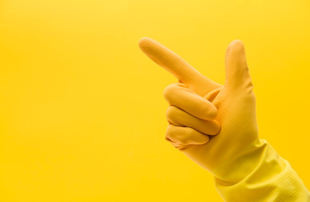 Pointing hand gesture made by a hand in a yellow rubber cleaning glove